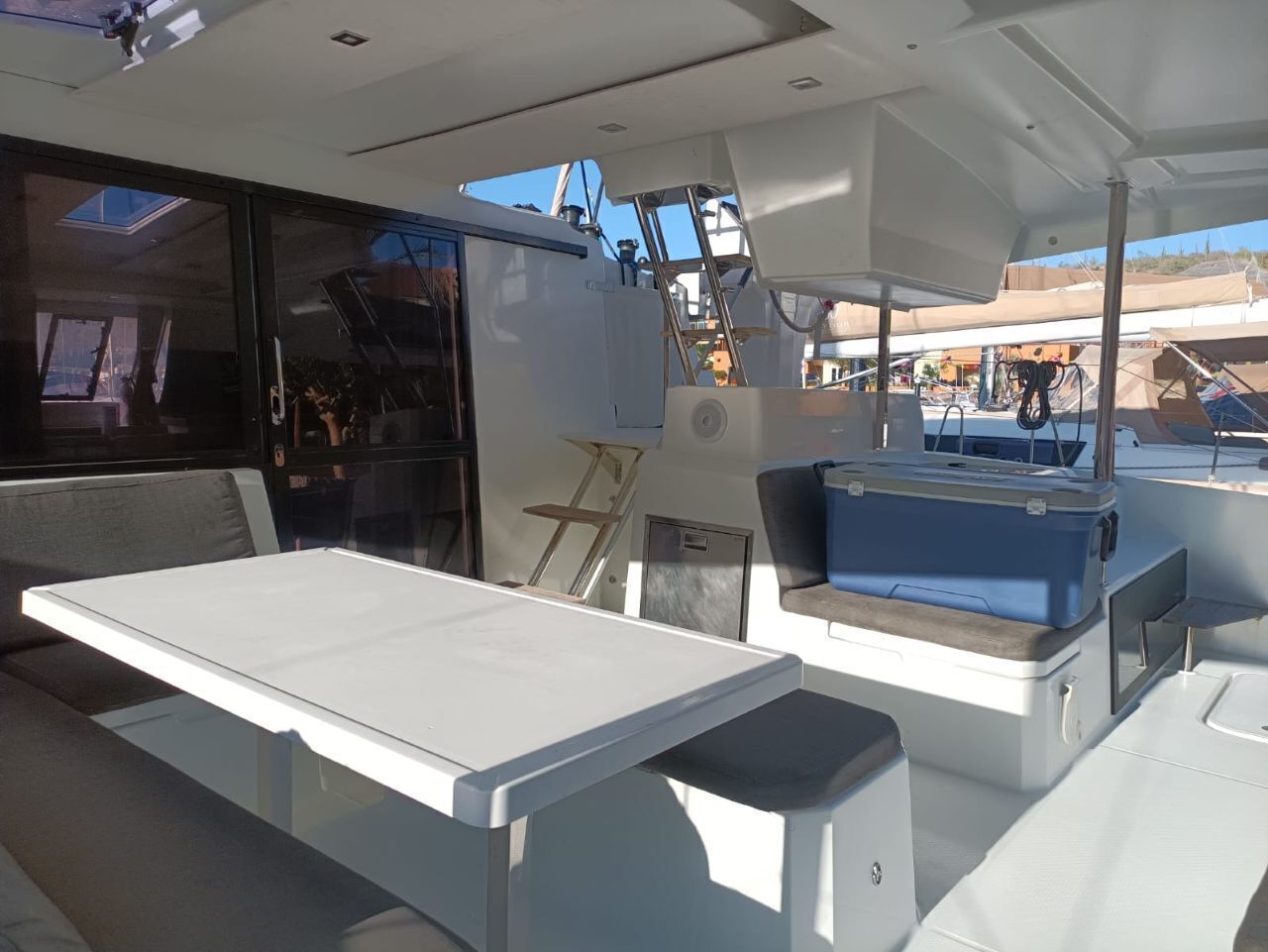Interior de barco com mesa, assentos e caixa térmica.