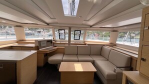 A yacht interior with a dining area, seating, a small kitchen, and large windows. - Caribbean Bliss: Sun-soaked Sailing Adventure from Granada, San Jorge (Saint George's)