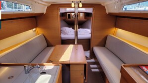 A compact interior with a bunk bed, a small table, and a sink. - Sun-Kissed Sailing Adventure in Split, Croatia (Kaštel Gomilica)
