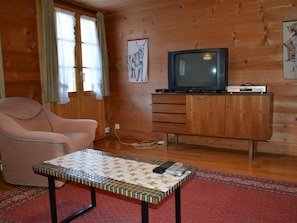 Ein gemütliches Wohnzimmer mit Fernseher, einer Couch, einem Schrank und einem Couchtisch mit Muster.