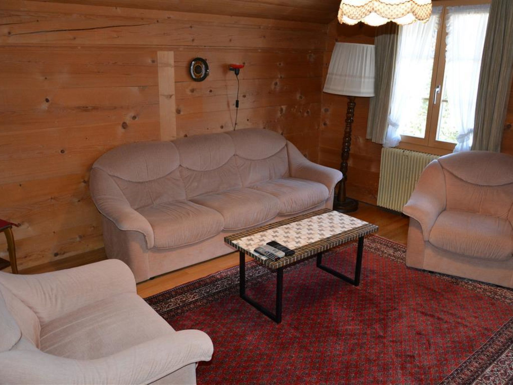 Una sala de estar acogedora con un sofá color beige, un sillón a juego y una mesa de centro con mantel estampado.