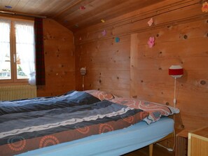 Ein Schlafzimmer einer Holzhütte mit einem Bett, einem Fenster mit Vorhängen und einer Wand mit dekorativen Elementen.