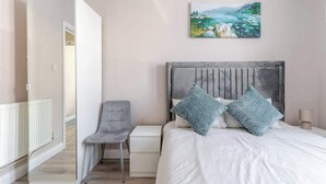 A bedroom with a bed, a chair, a nightstand, and a painting on the wall. - Central Bristol Luxury Apartment w/ Fast WiFi, (Redfield)