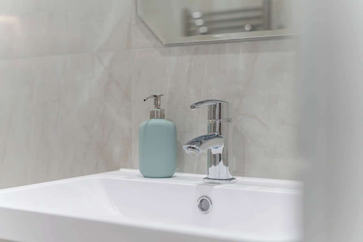 A bathroom sink with a chrome faucet and a soap dispenser.