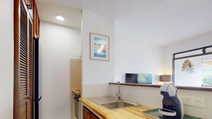 A compact kitchen with a wooden countertop, a sink, a coffee maker, and a framed picture on the wall. - Luméa Apartment (Les Trois-Îlets)