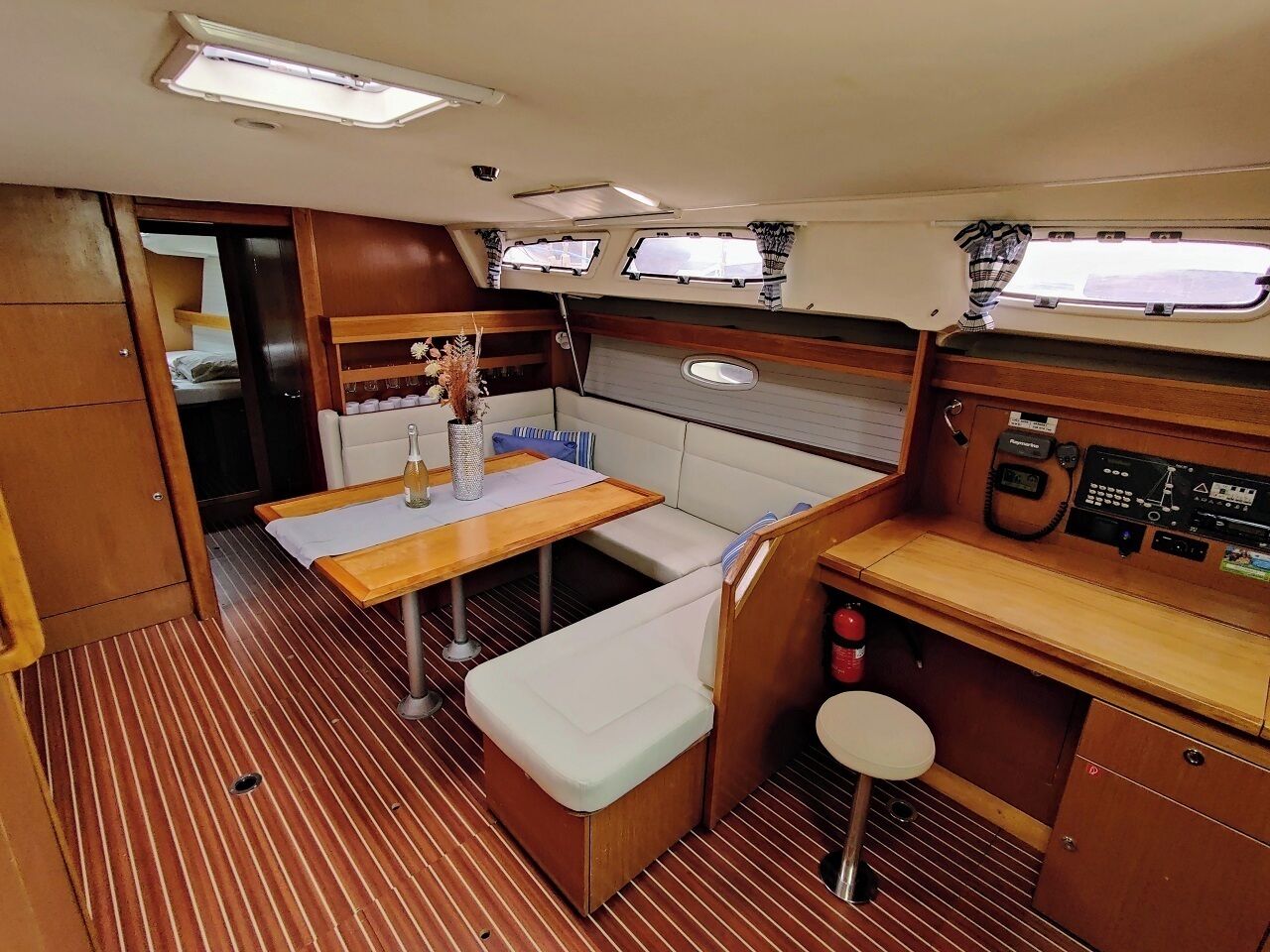 A compact galley with a wooden table, bench seating, and a control panel.