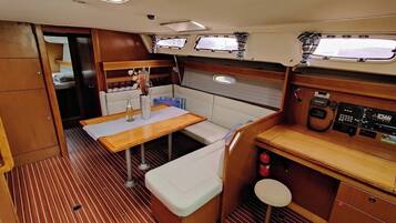 A compact galley with a wooden table, bench seating, and a control panel.