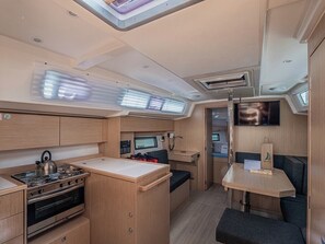 A compact kitchen with a stove, oven, and a small dining area with a table and seating. - Sun-Kissed Sailing Adventure in Zadar, Croatia (Zadar)