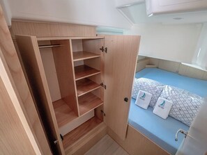 A compact room with a bed, a wardrobe with multiple shelves, and a small desk with a laptop. - Sun-Kissed Sailing Adventure in Zadar, Croatia (Zadar)