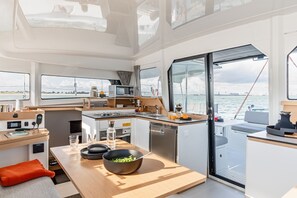 Eine moderne Kombüse mit Essbereich, Küchengeräten und Blick auf das Meer.