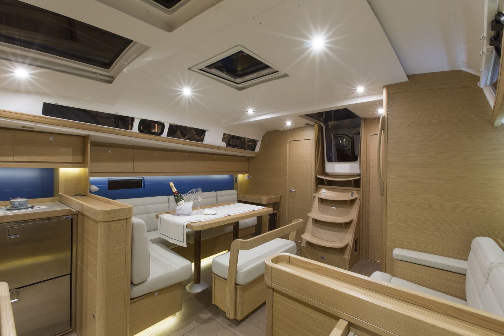 A compact RV interior with a kitchenette, seating area, and storage cabinets.