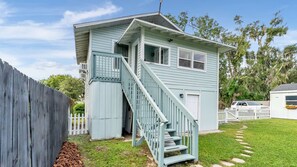 A light blue two-story building with a white exterior, a front porch, and a staircase leading to the entrance.