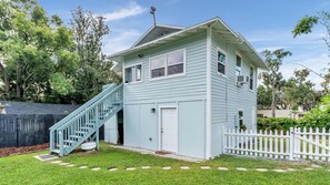A light blue two-story house with a white picket fence, a staircase, and a small porch.
