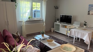 Un salon comprenant un canapé, une table basse, un téléviseur, une table à manger et un radiateur.