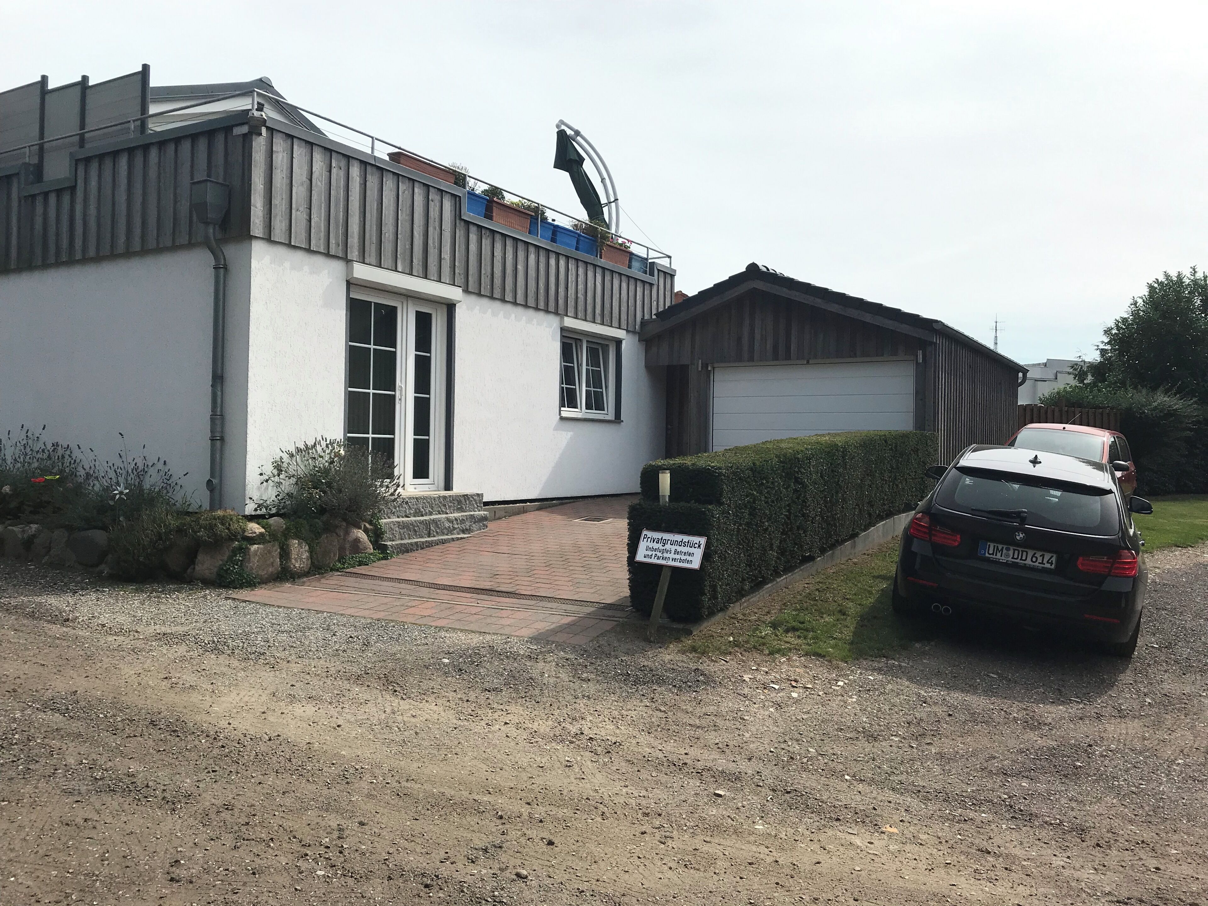 Ein Wohngebäude mit Garage, Auffahrt und einem geparkten Auto davor.