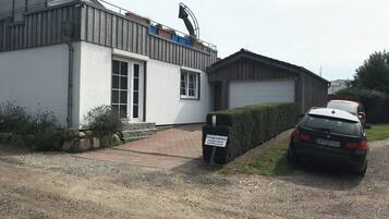 Ein Wohngebäude mit Garage, Auffahrt und einem geparkten Auto davor.