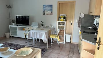 Ein gemütlicher Wohnbereich mit Essplatz, Küchenzeile und Fernseher.