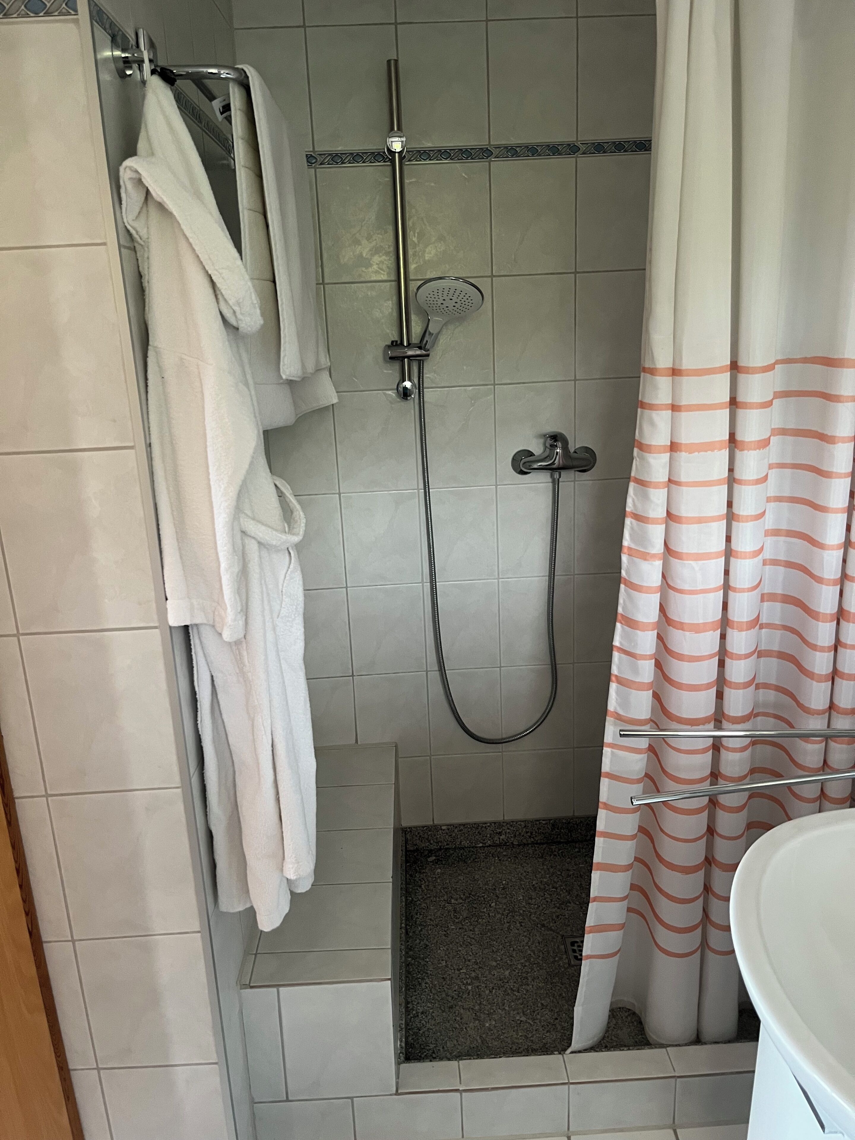 Ducha con cabezal de ducha de mano, grifo empotrado en la pared y cortina de baño.
