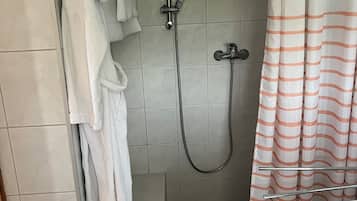 Ducha con cabezal de ducha de mano, grifo empotrado en la pared y cortina de baño.