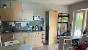 Une cuisine compacte avec des meubles de rangement en bois, un évier et un coin repas comprenant une table et des chaises.