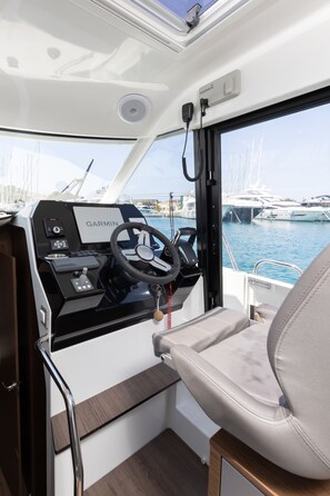 A boat's interior with a steering wheel, Garmin navigation system, and a view of the marina through the windows. - Sun-Kissed Sailing Adventure in Sibenik, Croatia (Rogoznica)