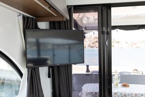 A television mounted on a wall inside a vehicle, with a view of the outside through a window. - Sun-Kissed Sailing Adventure in Sibenik, Croatia (Rogoznica)