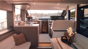 Interior de un yate con comedor, zona de estar y puesto de control.