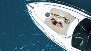 Een boot met zonnedek, een zitgedeelte en iemand die op het dek ligt.