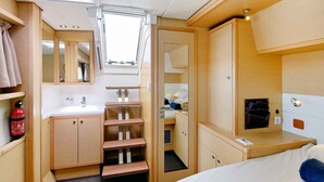 A compact RV interior with a bathroom, a bed, and a small kitchenette.