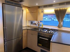 A compact kitchen with a stainless steel refrigerator, a gas stove, and a built-in oven.