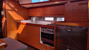 A compact kitchen with wooden cabinets, a stainless steel refrigerator, and a sink. - Sun-Kissed Sailing Adventure in Sibenik, Croatia (Zaton)