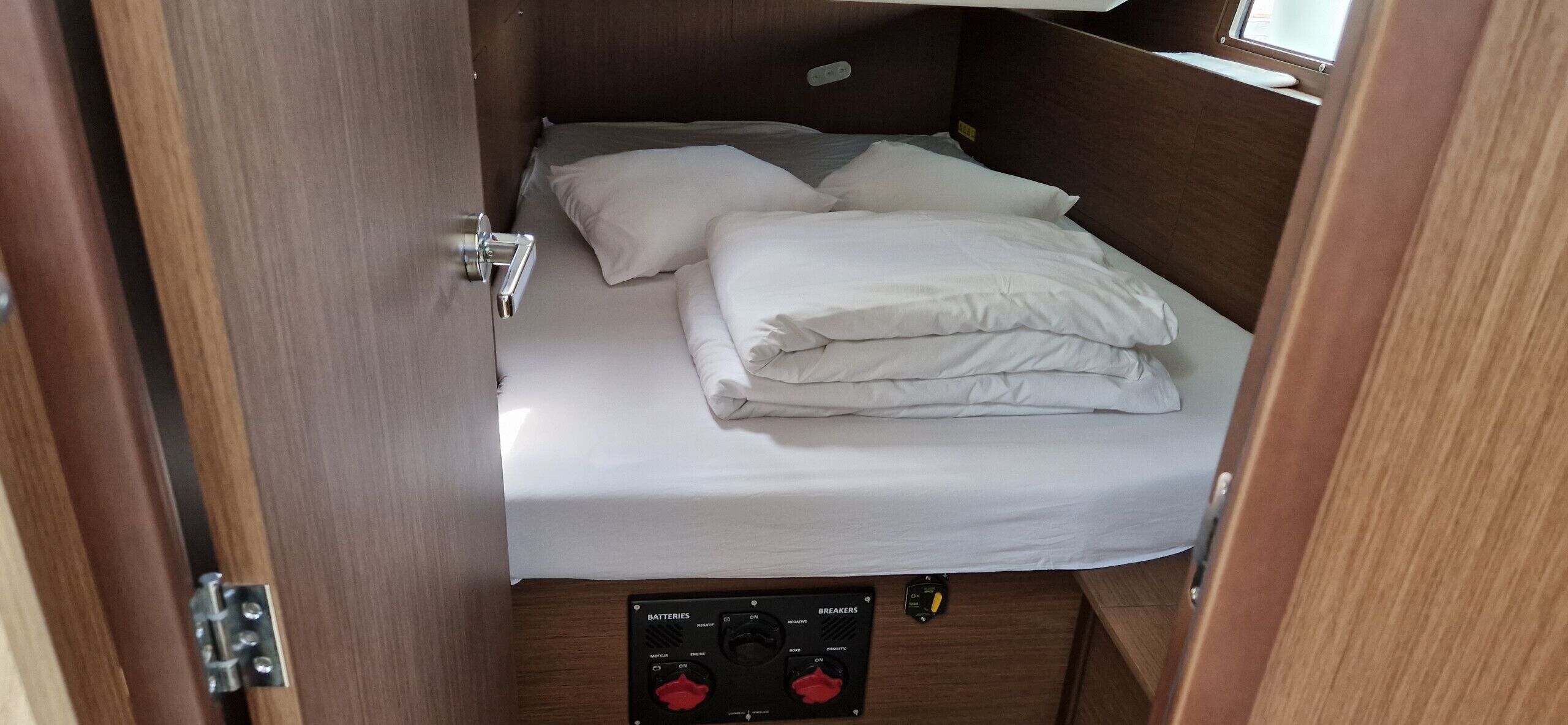 Een kleine kamer met een bed, een bedieningspaneel met knoppen en een raam.
