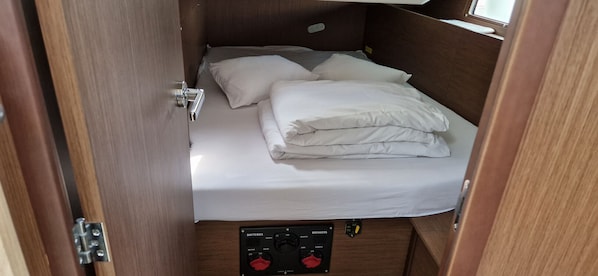 Une petite pièce comprenant un lit, un panneau de commande avec des boutons et une fenêtre.