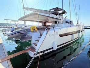 A white yacht named 'Aura 51' docked at a marina with other boats, a covered deck, and a wakeboard. - Sun-Kissed Sailing Adventure in Zadar, Croatia (Bibinje)