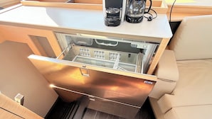Et kompakt køkken med et indbygget køleskab, kaffemaskine og vanddispenser.