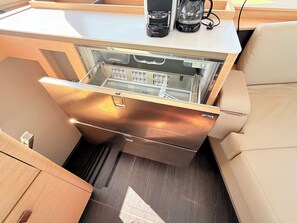 A compact kitchen with a built-in refrigerator, a coffee maker, and a water dispenser. - Sun-Kissed Sailing Adventure in Zadar, Croatia (Bibinje)