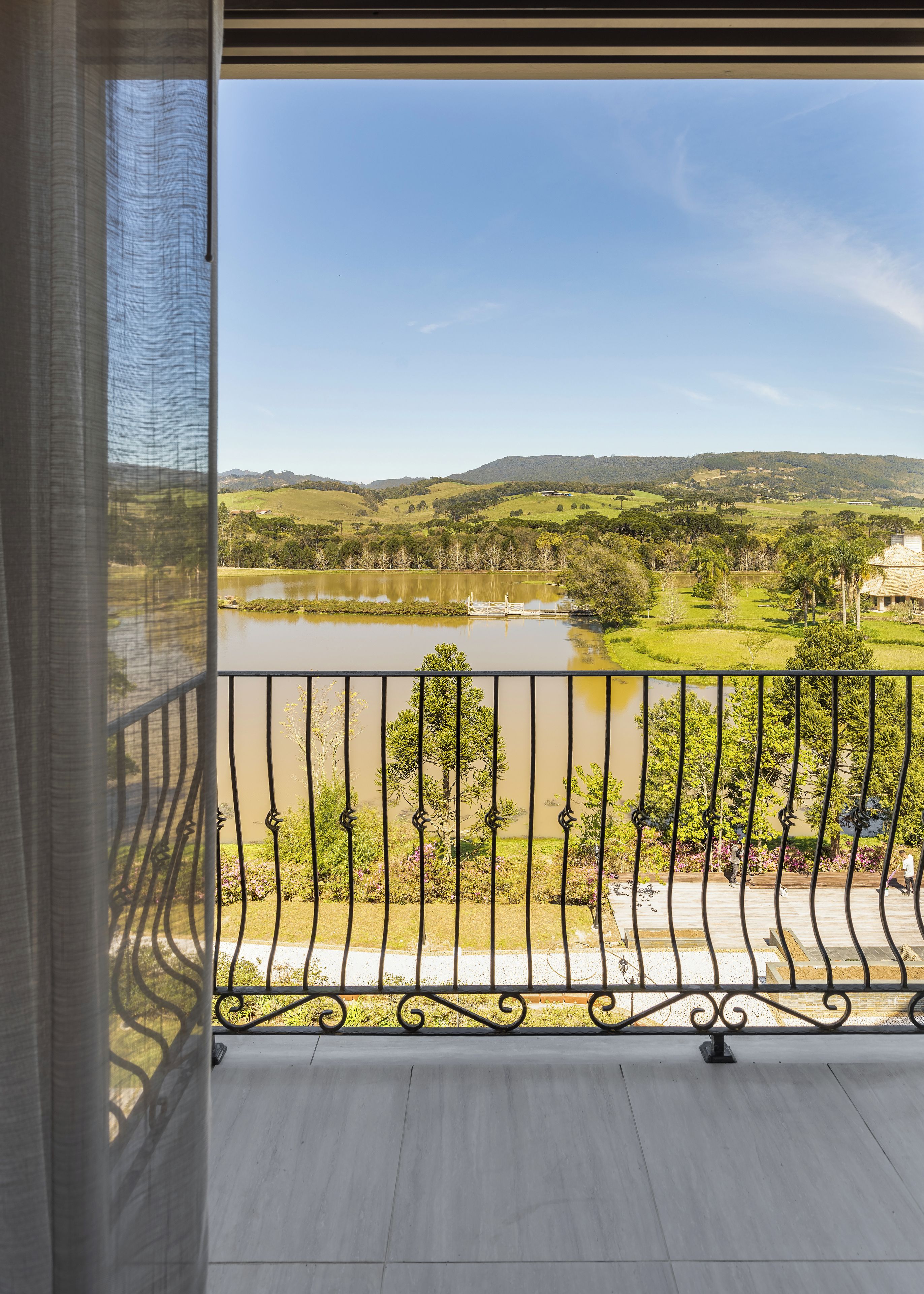 Un balcón con vistas a un lago, árboles y colinas.