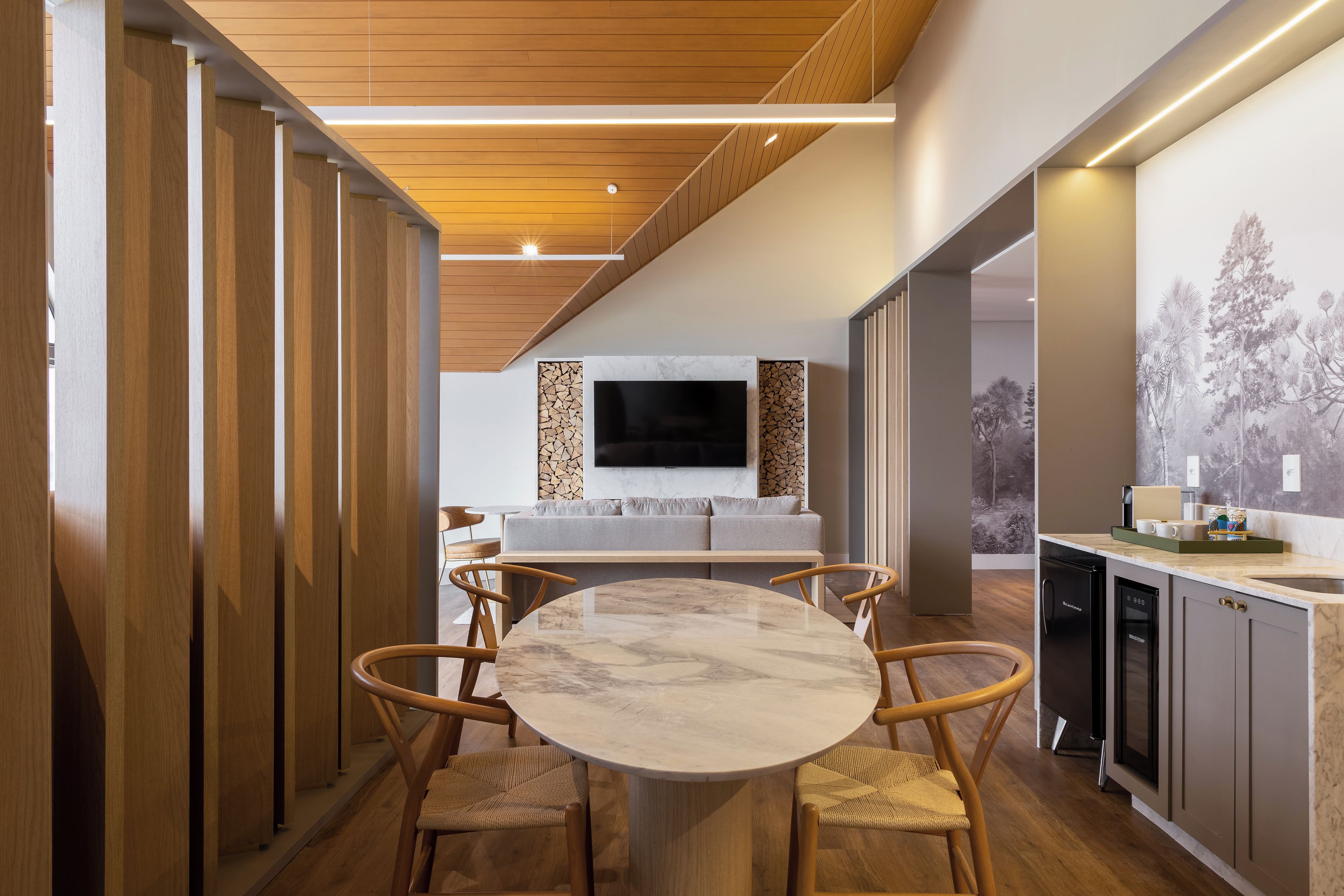 Une cuisine moderne avec une table ronde en marbre, des chaises en bois et un téléviseur encastré.