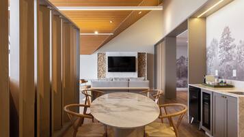 Une cuisine moderne avec une table ronde en marbre, des chaises en bois et un téléviseur encastré.