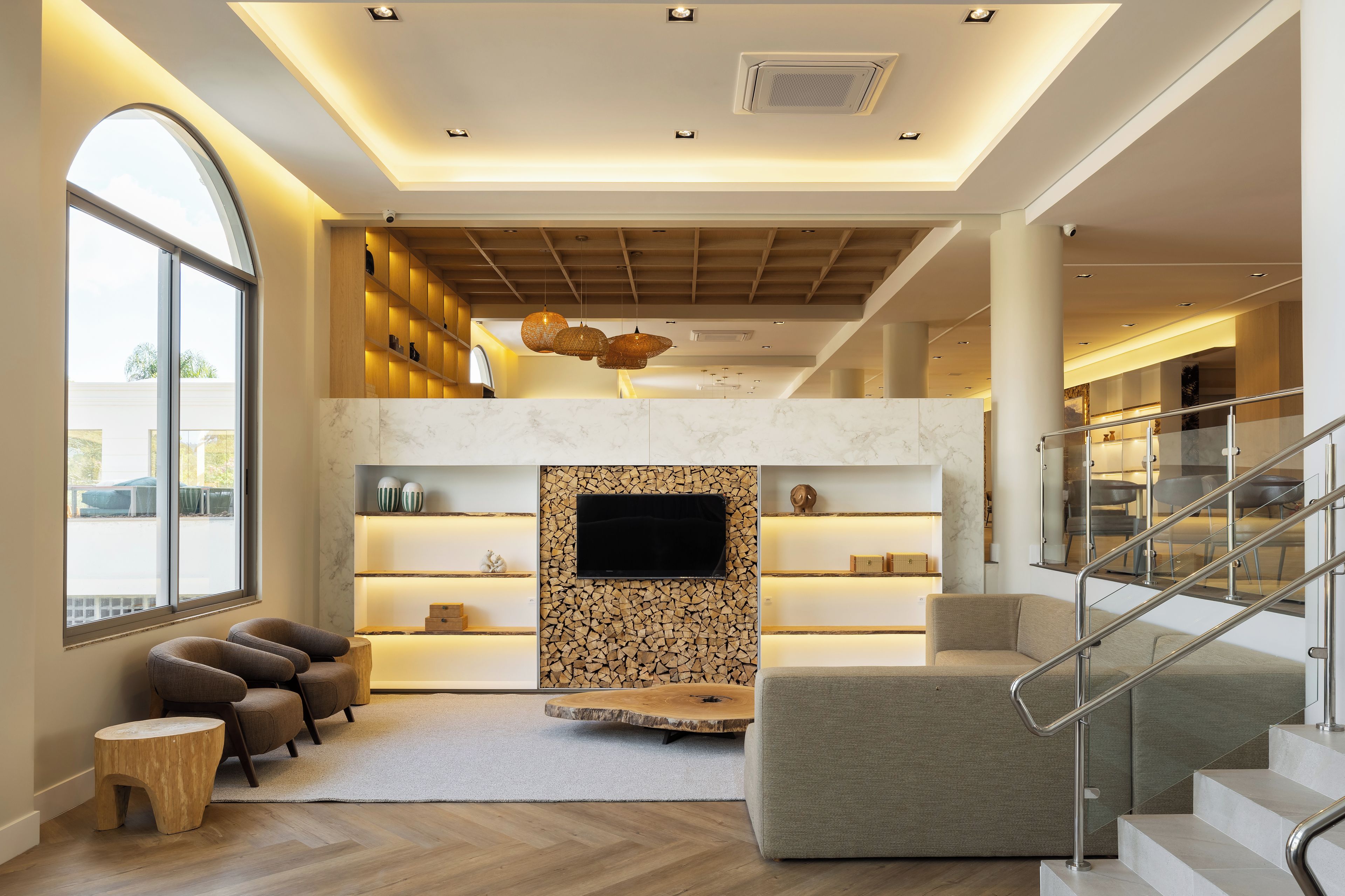 A modern living room with a fireplace, wooden shelves, and a large window.