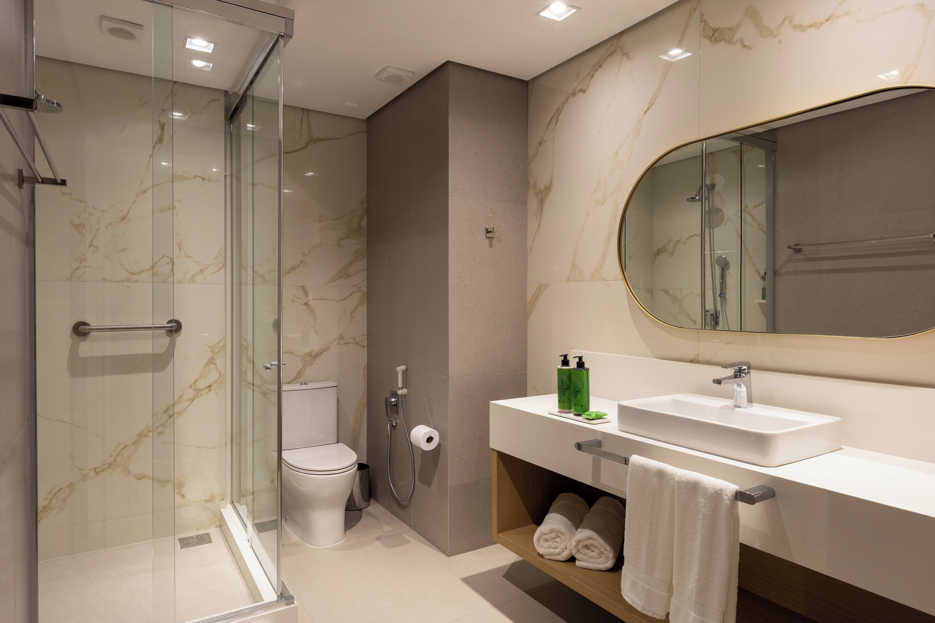 A modern bathroom with a glass-enclosed shower, a toilet, a sink with a mirror, and a towel rack.