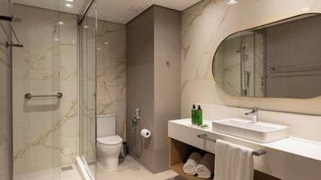 A modern bathroom with a glass-enclosed shower, a toilet, a sink with a mirror, and a towel rack.