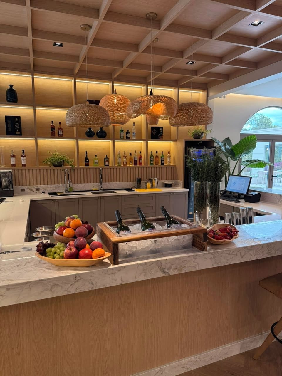 A modern kitchen with a marble countertop, a fruit bowl, and a wine cooler.