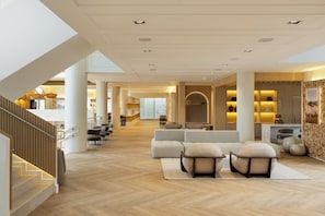 A spacious interior with a high ceiling, a staircase, and a seating area with sofas and ottomans.