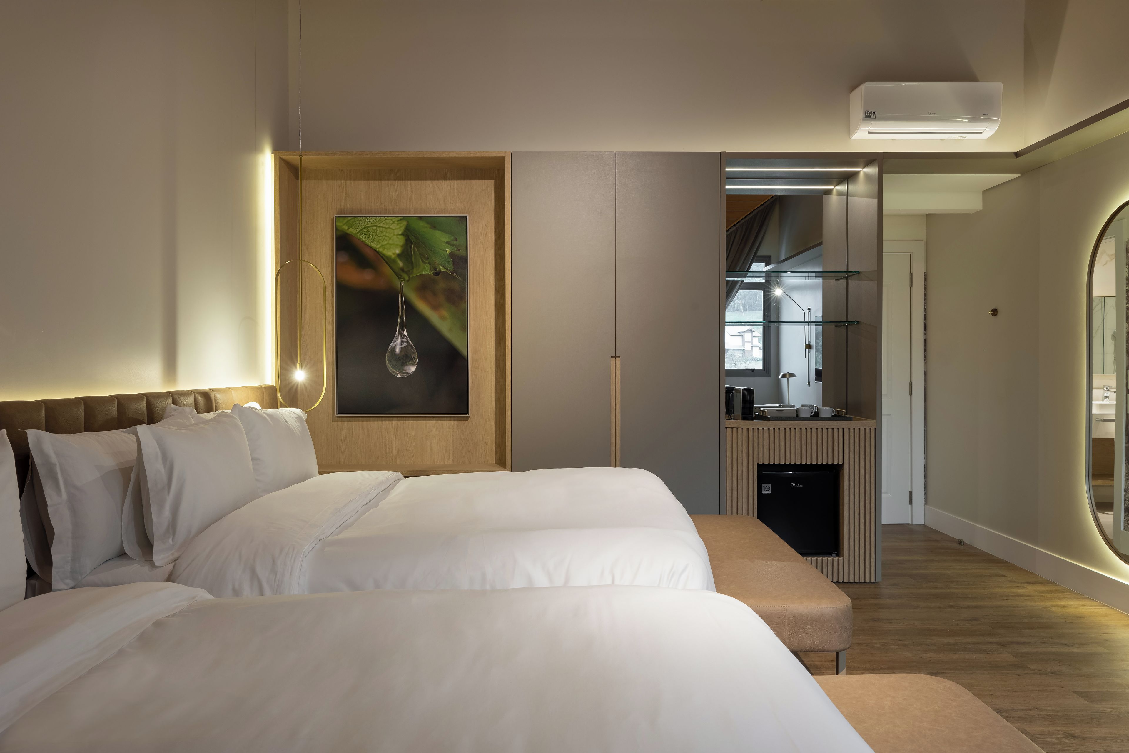 A modern hotel room with a large bed, a small kitchenette, and a view of the city.