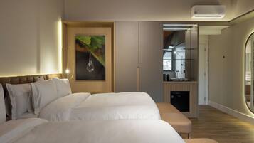 A modern hotel room with a large bed, a small kitchenette, and a view of the city.