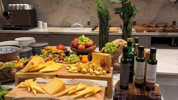 A buffet setup with various cheeses, fruits, and condiments.
