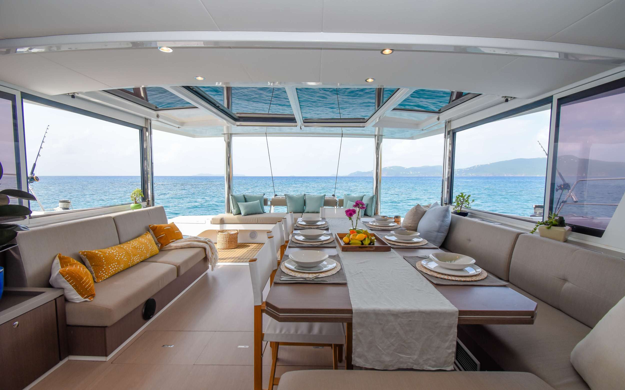 Interieur van een jacht met een eethoek, zitplaatsen en uitzicht op zee.