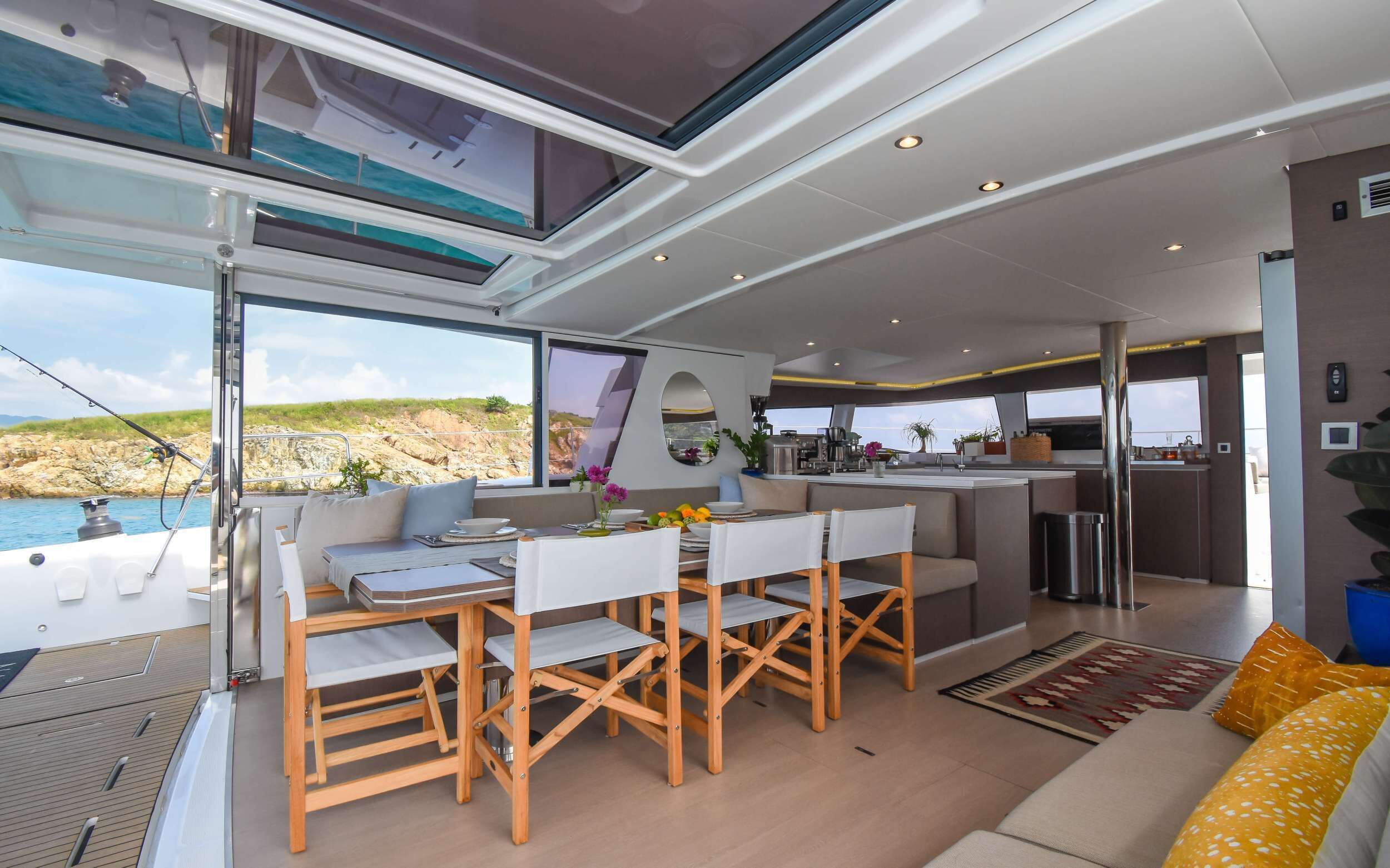 L’intérieur d’un yacht comprenant un coin repas, une cuisine et une vue sur la mer.
