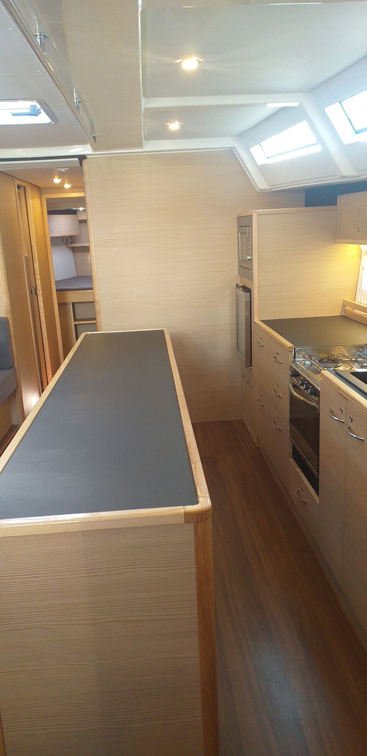 A compact kitchen with a built-in stove, a microwave, and a small refrigerator. There is a skylight above the counter, providing natural light.